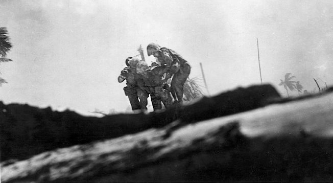 Two Marines help a wounded buddy to a place of safety during the fierce fighting on Tarawa. Nearly 1,000 Marines were killed in the three-day battle and over 2,000 were wounded. The enemy force fared far worse. 