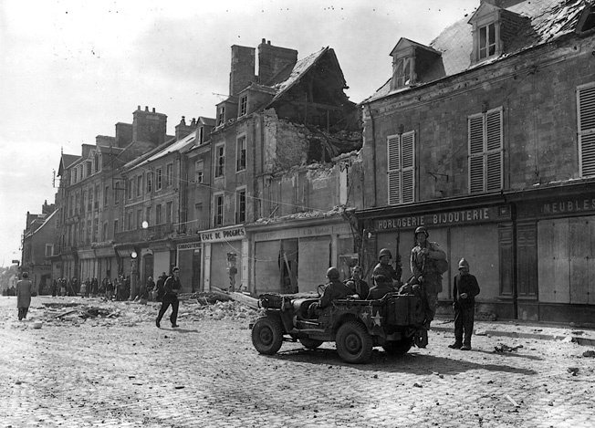 Several of them arriving aboard a jeep, troops of the 101st Airborne Division enter the important Norman town of Carentan on June 14, 1944.