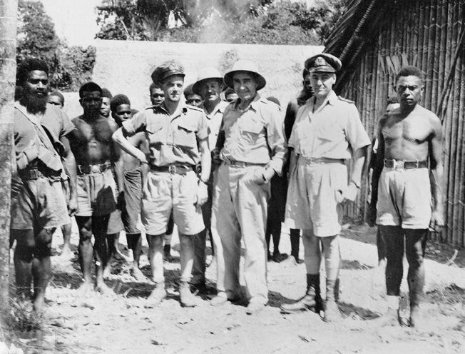Lt. Cmdr. W.J. "Jack" Read of the Royal Australian Navy Intelligence Division poses (hand on hip) with other personnel, including native scouts, at the Australian Intelligence Bureau Camp at Lunga, Guadalcanal, on March 27, 1945.