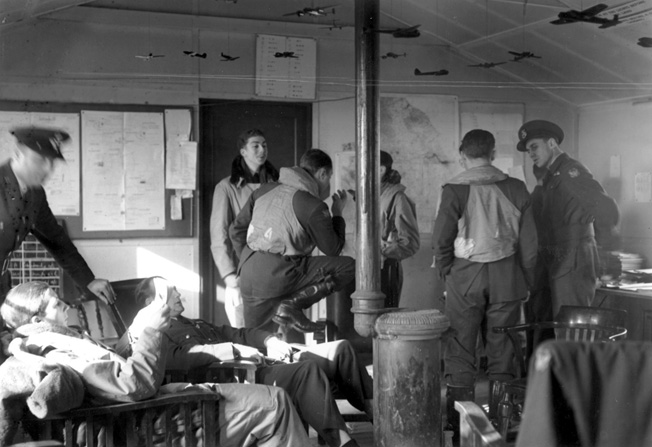 Eagle Squadron pilots engage in lively chatter and lounge around a dispersal hut as they await the word to take off on a training flight.