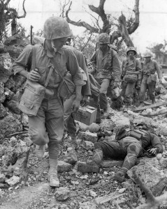 Pressing forward, U.S. Marines glance at the body of a dead Japanese soldier on May 24, 1945. At the time this photo was taken, another grueling month of fighting and dying remained before Okinawa was declared secure.