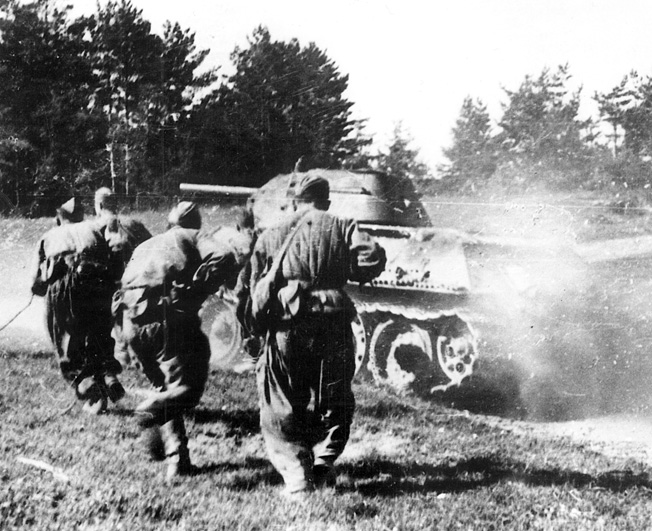 An advancing T-34 tank stirs up a cloud of summertime dust as Red Army soldiers crouch behind it. The Soviet armed forces mounted a devastating offensive in 1944, which carried them to the gates of Berlin.