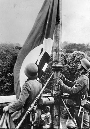 German soldiers raise the Nazi flag in Belgium. The invasion of France and the Low Countries on May 10, 1940, resulted in the swift conquest of those nations. The might of Nazi arms was well illustrated with the magnificent assault by German glider troops on Fort Eben Emael on the Belgian-Dutch frontier.