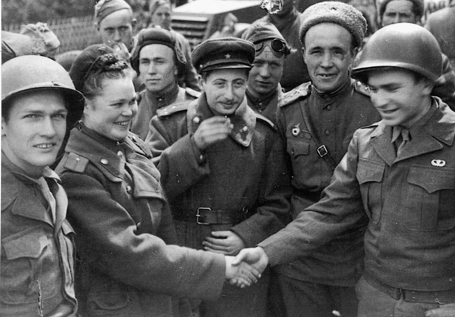 Manfred Steinfeld (right) shakes hands with a female Soviet soldier as East and West meet at the Elbe River, May 2, 1945. 