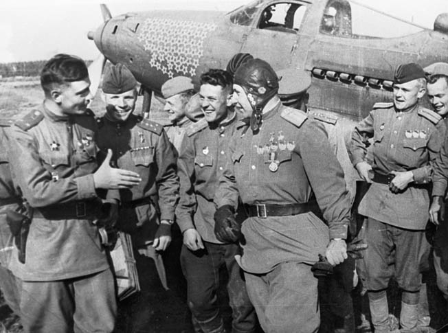 His P-39 emblazoned with victory stars stands in the background as Soviet fighter ace Alexander Pokryshkin talks with ground personnel after returning from a mission against the Germans on the Eastern Front during World War II.