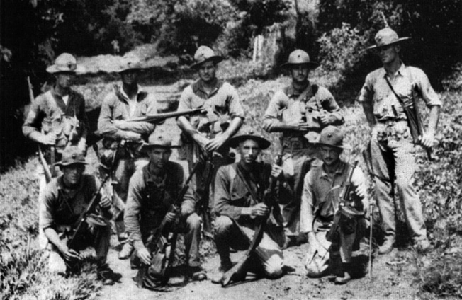 A jungle-wise Marine patrol poses with its weapons, including submachine guns.