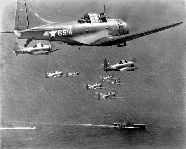above: A flight of Douglas SBD Dauntless dive bombers from the aircraft carrier USS Enterprise flies above the carrier and other ships of its task force during a training exercise.
