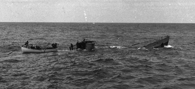 After their U-boat quarry has sustained damage from an effective depth charge attack and risen to the surface, crewmen of the Spencer pick up survivors before the stricken submarine plunges to the bottom of the Atlantic. 