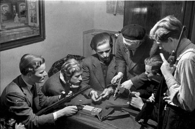  A group of Danish resistance fighters in a “safe house” in the city of Odense on the island of Fyn are instructed in the use of various weapons.